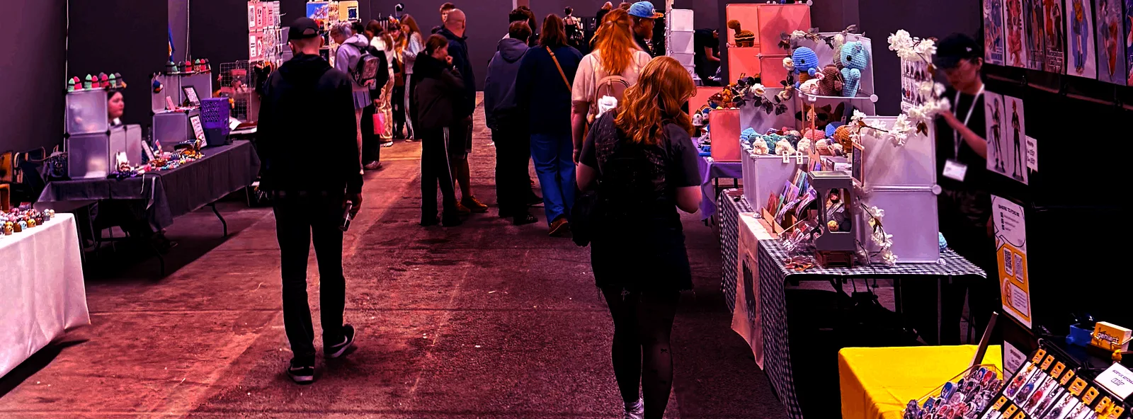 Gangen gennem Artist Alley med besøgende, der kigger på hæklede bamser, prints og smykker ved artisternes borde